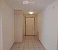 Empty hallway with tiled floor, white walls, and a closed door leading to another room.