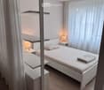 Modern bedroom with a white bed, nightstands, lamps, and sheer curtains on large windows.