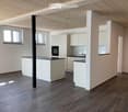 Modern kitchen with white cabinets, dark countertops, and wooden flooring.