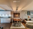 Modern open-plan living and dining area with a sofa, dining table, chairs, kitchen area, and artwork on the walls.