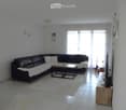 Modern living room with a black leather sectional sofa, a wooden coffee table, a TV stand, and a white rug.