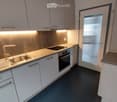 Modern kitchen with white cabinets, stainless steel sink, faucet, and built-in oven. Countertop with integrated lighting and a door leading outside.