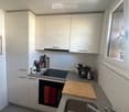 Modern kitchen with white cabinets, stainless steel sink, oven, and various kitchen items on the counter.