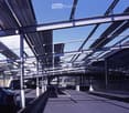Modern covered parking area with metal framework and several parked cars.