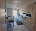 Modern kitchen with white cabinets, tiled floor, and a small dining area with a table and chairs.