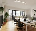 Bright, modern office space with large windows and a balcony view, featuring a white table, black chairs, laptops, and potted plants.