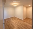 Empty room with light wooden flooring, white walls, and a single ceiling light fixture. No furniture or personal items are present.