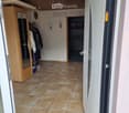 Hallway with tiled floor, wooden coat closet, and a sign that reads "WILLKOMMEN ZU HAUSE".