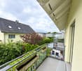 Balcony with metal railing, small wooden planters, and a view of a garden and neighboring houses.
