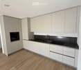 Modern kitchen with white cabinets, wooden flooring, and a black countertop featuring a sink and oven.