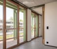 Modern hallway with large glass sliding doors leading to a balcony area, white walls, and carpeted floor.