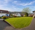 Well-maintained garden with a neatly trimmed lawn, a brick pathway, and surrounding houses with white walls and dark roofs.