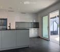 Modern kitchen with white cabinets, stainless steel oven, and a large sliding glass door leading to a balcony.