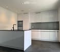 Modern kitchen with white cabinets, a central island, and built-in appliances including an oven and sink.