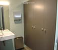 Modern bathroom with a white sink, mirror, and paper towel dispenser mounted on the wall. Features a built-in storage cabinet with silver handles.