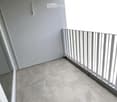 Empty balcony with tiled floor and white metal railing, featuring a light fixture on the wall.