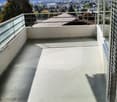 Balcony with a panoramic view of a city and mountains, featuring a glass railing and a hanging light fixture.