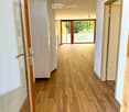 large hallway with wooden floors, glass sliding doors, tall windows with balconies