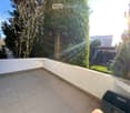 sunlit balcony with tiled floor, white walls, greenery and trees in the background