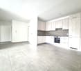 Empty kitchen with light-colored cabinets, tiled floor, and built-in oven. No furniture or appliances present.