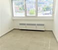 Empty room with tiled floor, white walls, large windows with blinds, and a radiator unit against the wall.