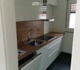 Modern kitchen with white cabinets, wooden countertop, stainless steel sink, and built-in dishwasher.