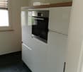 Modern kitchen with white cabinets, a built-in oven, and dark tiled flooring.