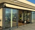 Modern glass-enclosed balcony with retractable awning, large windows, and indoor furniture visible through the glass.