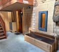 Wooden hallway with a bench, mirror, and cabinet, featuring a staircase leading upwards and a door to another room.