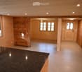 Empty room with wooden walls, tiled floor, and large windows. No furniture or equipment present.