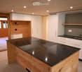 Modern kitchen with a central island, black granite countertop, white cabinets, and a sink with a modern faucet.
