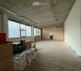 Empty room with bare walls, concrete floor, large windows, and some stacked boxes and crates in the corner.