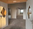 Empty room with bare walls, concrete floor, and open doors leading to other rooms.