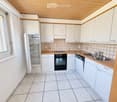 Modern kitchen with white cabinets, light wooden countertops, tiled backsplash, and stainless steel appliances including a refrigerator, oven, dishwasher, and sink.