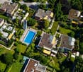Aerial view of a residential area with multiple houses, a swimming pool, and well-maintained gardens.