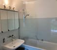 Modern bathroom with a white sink, mirror cabinet, bathtub, and glass shower enclosure.