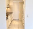 Modern kitchen with light-colored cabinets, a sink, and an oven, featuring tiled flooring and recessed lighting.