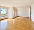 Empty room with wooden flooring, large windows, and white walls. No furniture or equipment present.