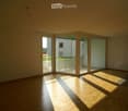 Empty room with wooden flooring and large sliding glass doors leading to a balcony area.