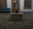 Courtyard with a stone fountain, wooden bench, and building with large windows and doors.