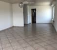 Empty room with tiled floor and white walls, featuring a modern chandelier and a doorway leading to another room.