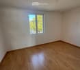 Empty room with wooden flooring and a single window showing a tree outside. No furniture or equipment present.