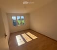 Empty room with wooden flooring and a large window showing a view of the outdoors.