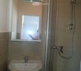 Modern bathroom with a white sink, a large mirror cabinet, and a glass-enclosed shower with a handheld showerhead.