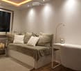 Modern, compact living space with a sofa bed, desk, chair, small table, and floor lamp. Features large window, neutral tones, and built-in storage under the sofa.
