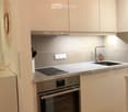 Modern kitchen with white cabinets, stainless steel appliances, and a sleek design. Features an induction cooktop, oven, and a sink with a modern faucet.