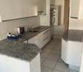 Modern kitchen with white cabinets, granite countertops, and a stainless steel sink.