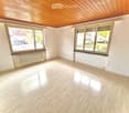 Empty room with light wooden flooring, white walls, large windows, and a radiator. No furniture or equipment present.