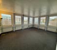 Empty room with multiple windows and a carpeted floor.