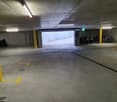 Underground parking lot with bikes parked on the right side, parking slots indicated by yellow markings, and ceiling lights installed.
